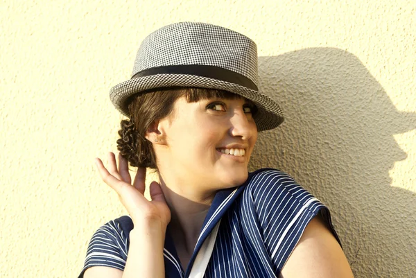 W pobliżu ściany szczęśliwy brunetka dziewczynka kapelusz — Zdjęcie stockowe