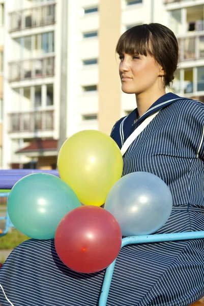 На качелях красивая девушка с воздушными шарами — стоковое фото