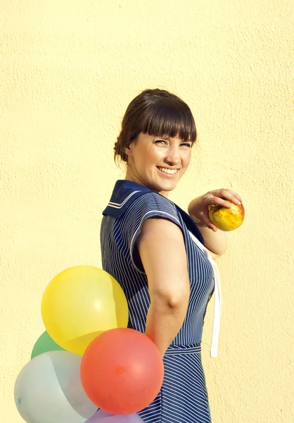 Bruneta dívka na pozadí zdi drží jablko a — Stock fotografie