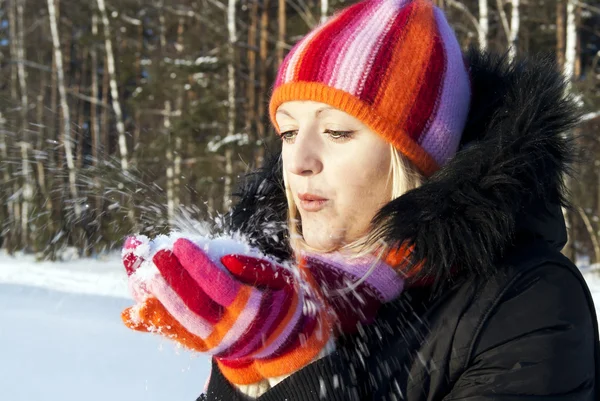 Het meisje in de winter blaast de sneeuw — Stockfoto