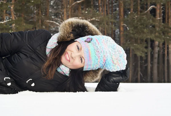 Het meisje liggen in de sneeuw in de winter — Stockfoto