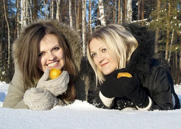 Две девушки едят грушу в снегу — стоковое фото