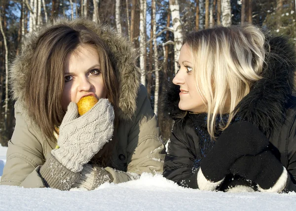Två flickor i snön äta ett päron och svartsjuk — Stockfoto