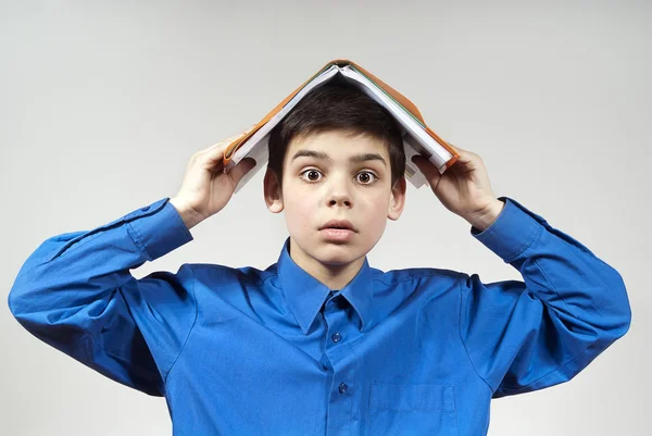 Мальчик держит книгу на голове — стоковое фото