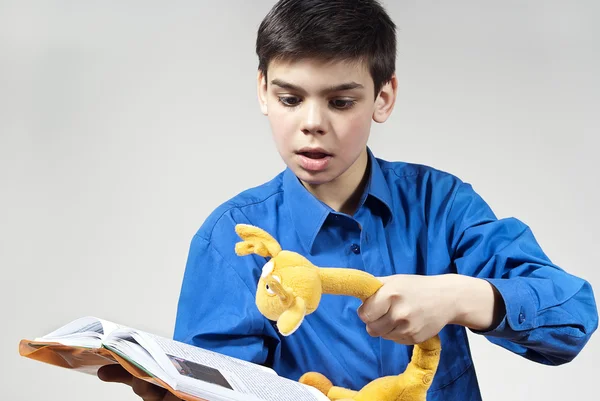 Αγόρι με ένα βιβλίο και ένα παιχνίδι σε γκρι φόντο — Φωτογραφία Αρχείου