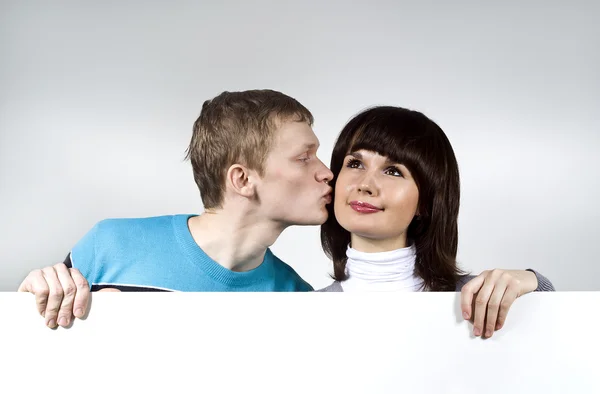 The man and the woman points to the background, kissing — Stock Photo, Image