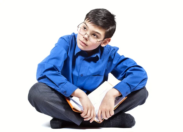 En pojke sitter och läser en bok — Stockfoto