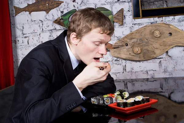 Красивый парень в ресторане ест суши — стоковое фото