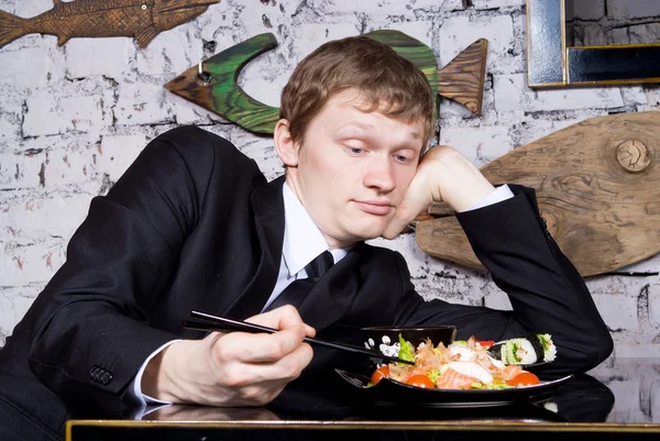 Un bel ragazzo al ristorante si affaccia sul sushi — Foto Stock