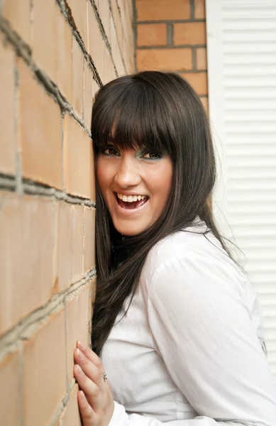 Portret pięknej dziewczyny szczęśliwy brunetki w pobliżu ściany — Zdjęcie stockowe