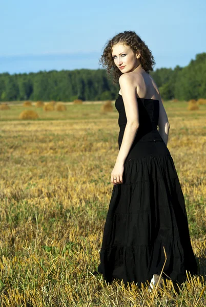 Vackra curly-haired girl på fältet visar — Stockfoto