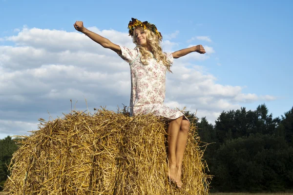 Beautiful girl blonde sitting on a hay — Stock Photo, Image
