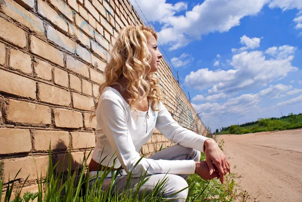 Piękna dziewczyna siedzi w pobliżu ściany o charakterze — Zdjęcie stockowe