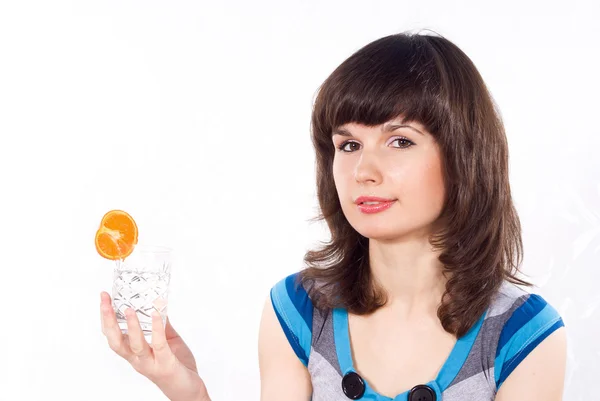 Chica sosteniendo un vaso de agua con una mandarina — Foto de Stock