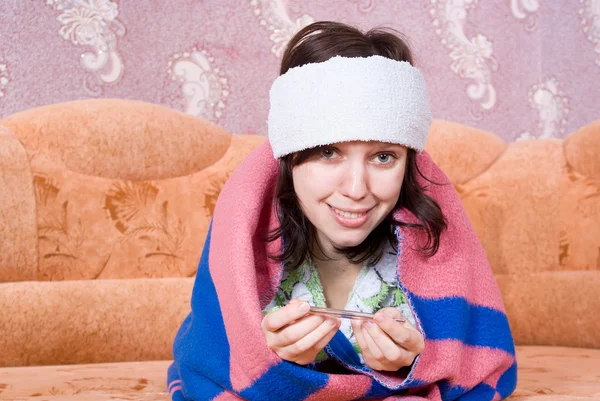 Girl lying on the couch sick with a thermometer — Stock Photo, Image