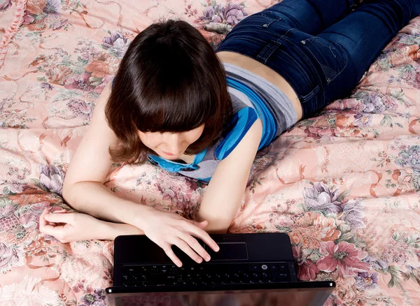 Girl on the bed with a laptop working — Stock Photo, Image