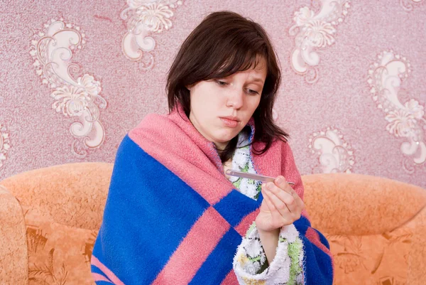 Nemocná holka na gauči s teploměrem — Stock fotografie