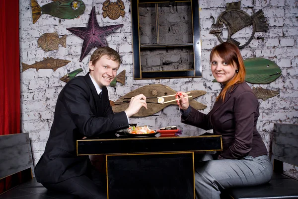 stock image The guy with the girl eat sushi