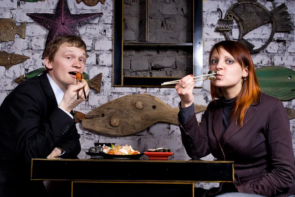 Stock image The guy with the girl eat sushi