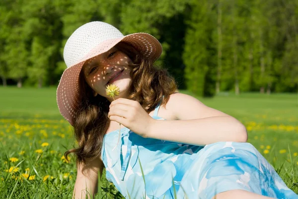 Egy fiatal lány feküdt, egy réten, és tartja a virág — Stock Fotó