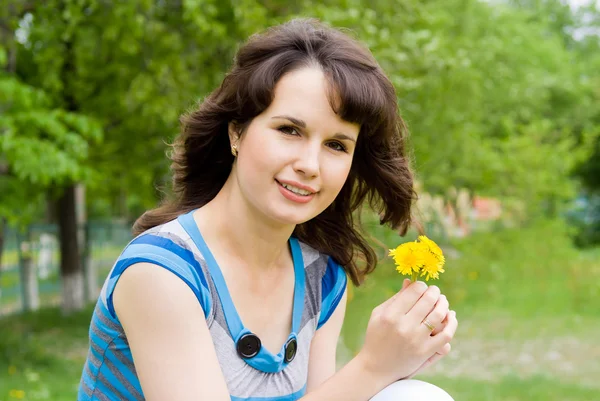 Beautiful girl holding flowers, in nature — Stock Photo, Image
