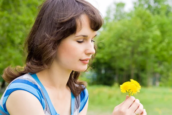 Hermosa chica mirando las flores, en la naturaleza — Foto de Stock