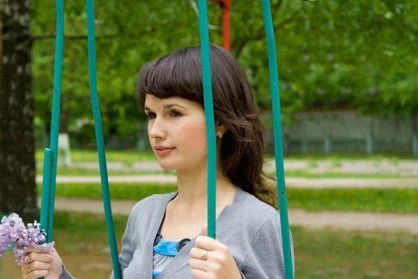 Beautiful girl sitting on a swing, in nature — Stock Photo, Image