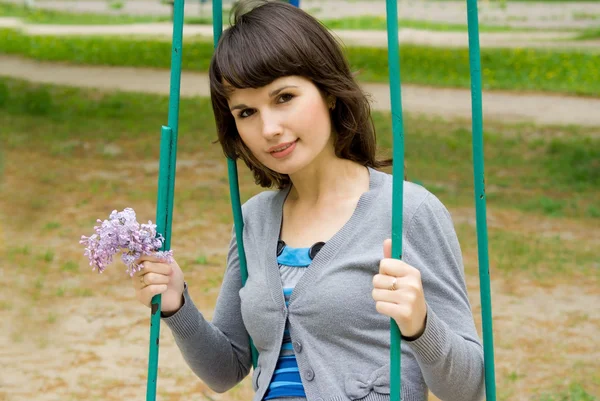 Beautiful girl sitting on a swing, in nature — Stock Photo, Image