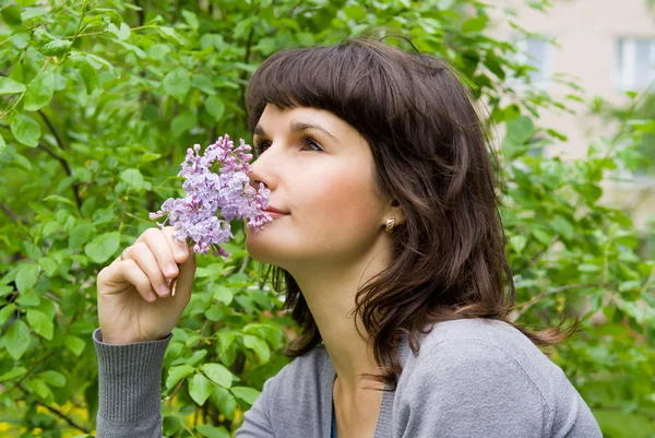 Menina bonita cheirar os lilases, na natureza — Fotografia de Stock