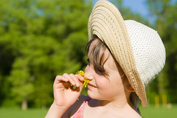 Dziewczyna w kapeluszu pachnący kwiat, w przyrodzie — Zdjęcie stockowe