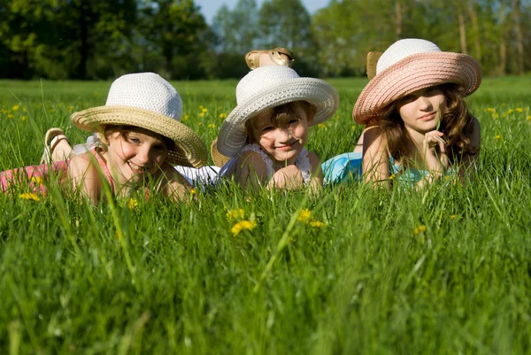 Três meninas jazem na grama, na natureza — Fotografia de Stock