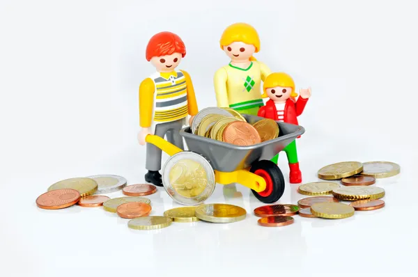 Kinderbijslag - playmobil familie en een kruiwagen gevuld met munten — Stockfoto