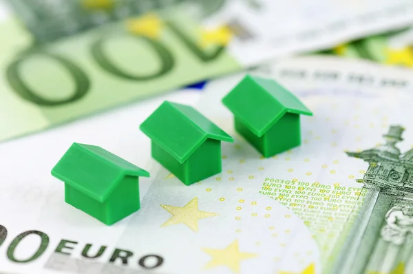 Három zöld modell ház és 100 euro bankjegyek — Stock Fotó