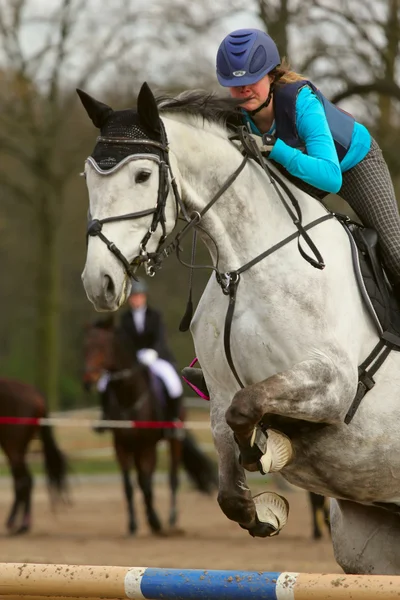 De rider vrouw springt met witte paard over een belemmering — Stockfoto