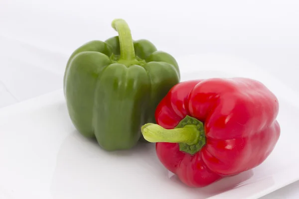Green and red paprika on the white bowl. — Stock Photo, Image