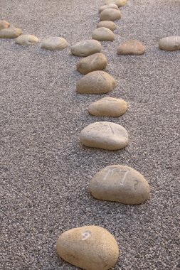 Çince harflerle kazınmış kaya parçaları çakılların üzerinde duruyordu.