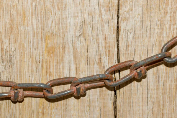 Una catena su uno sfondo di legno incrinato — Foto Stock