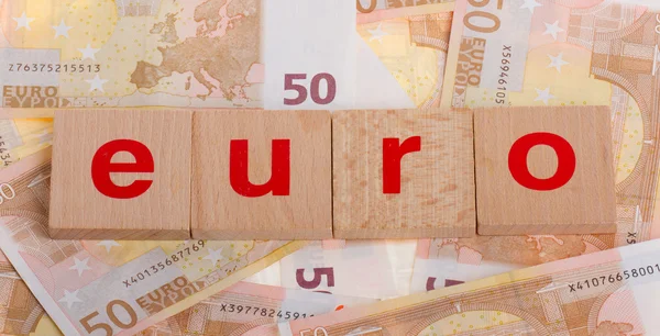 stock image Letter on blocks on top of some 50 euro banknotes