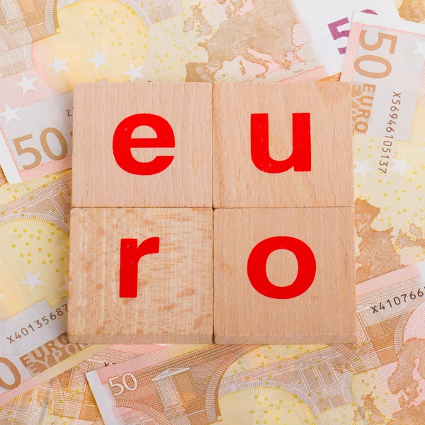 Letter on blocks on top of some 50 euro banknotes — Stock Photo, Image