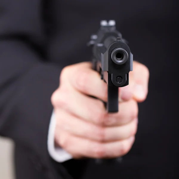 Man with gun, business suit, focus on the gun — Stock Photo, Image