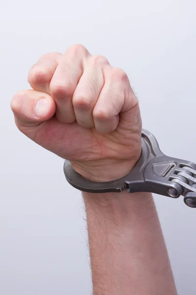 A man in metal handcuffs on a grey background — Stock Photo, Image
