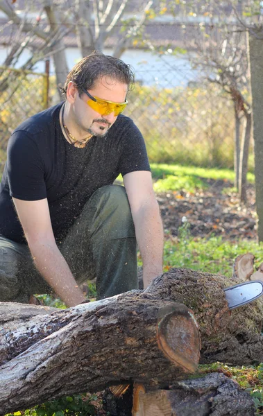 Mann hackt Holz mit Motorsäge — Stockfoto