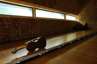 Violoncello laying on the floor in empty classroom clipart