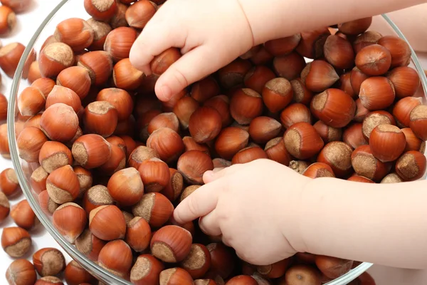 Top view of baby's hands touching hazelnuts — Stock Photo, Image