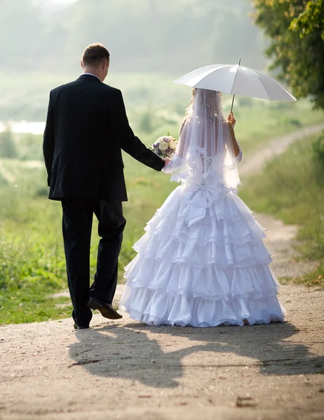 Braut und Bräutigam gehen im Sonnenlicht — Stockfoto