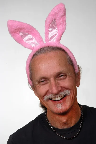 Hombre sonriente con orejas de conejo rosa — Foto de Stock