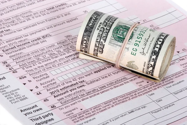 A roll of USD cash near an IRS tax form Stock Photo