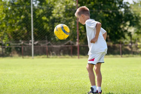 Lapsi pelaa jalkapalloa — kuvapankkivalokuva