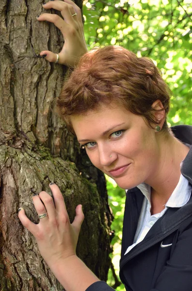 Ung kvinna att posera bredvid trädet. — Stockfoto