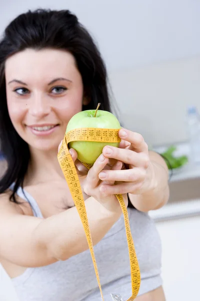 Young woman measuring an apple — Stock Photo, Image